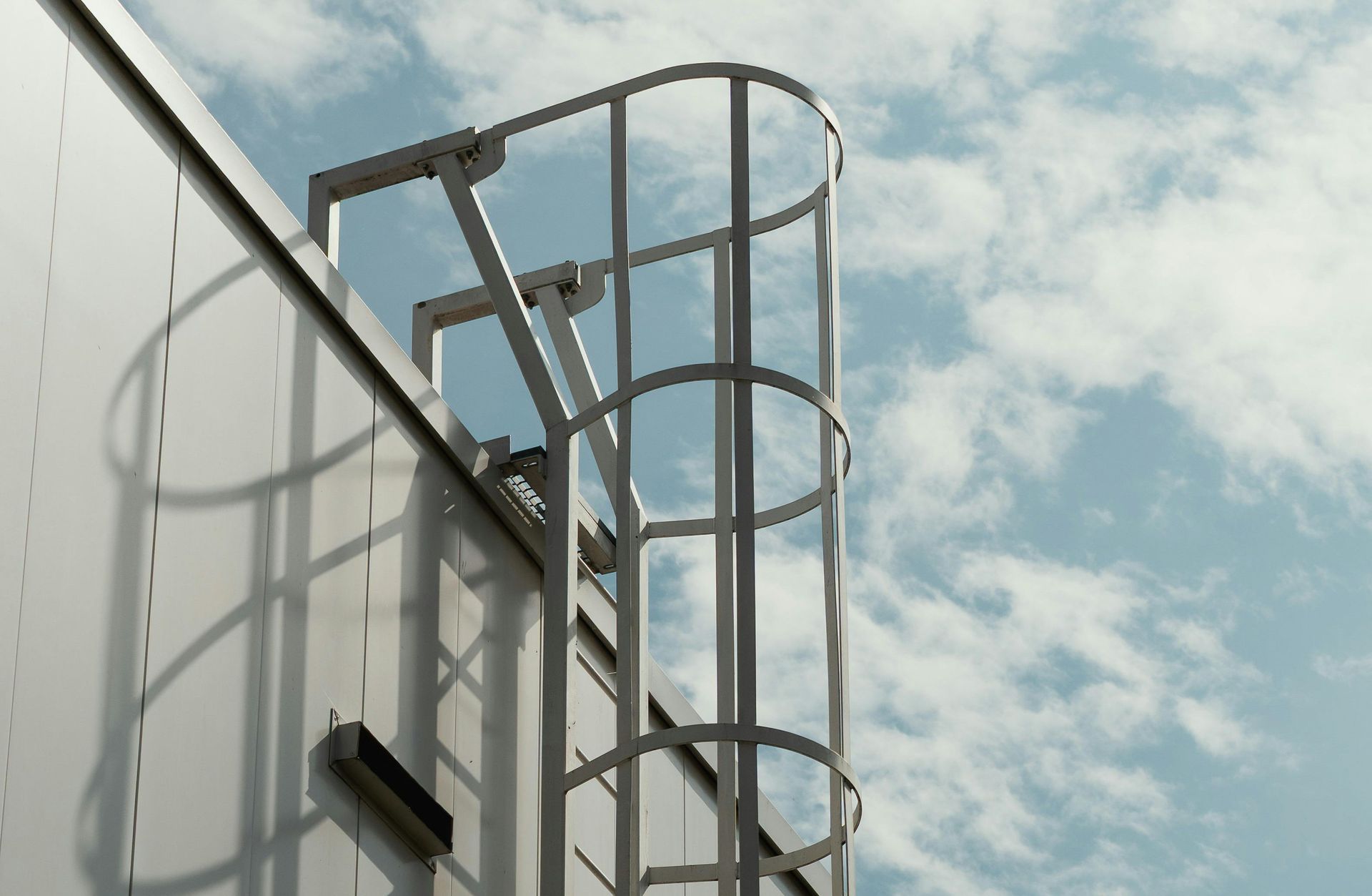 White ship deck with a metal ladder and railings against a cloudy sky