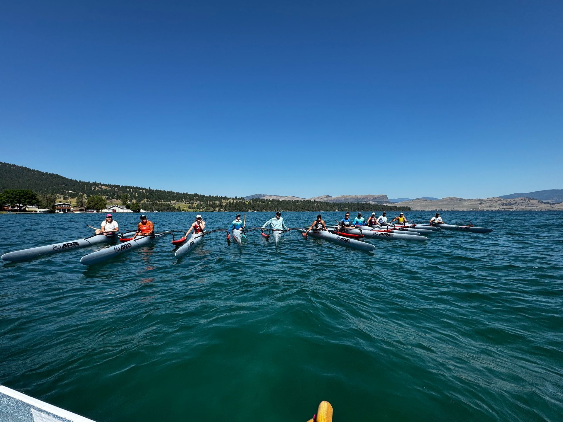 A group of people are rowing kayaks on a lake.