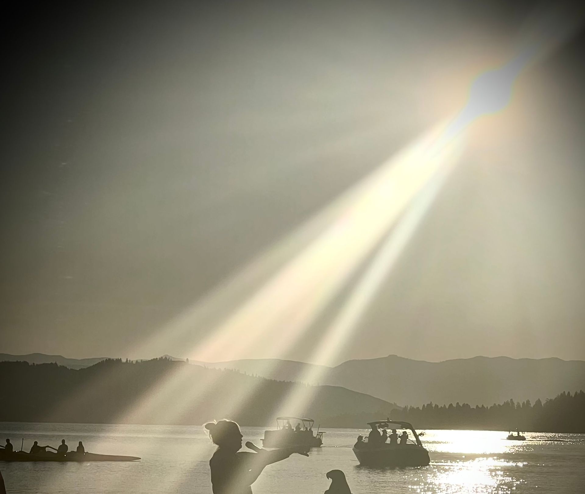 The sun is shining through the clouds over a body of water