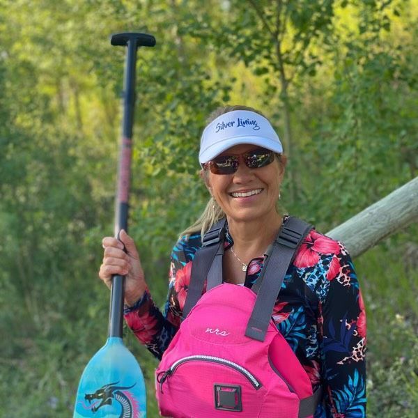 A woman is holding a paddle and a pink backpack.
