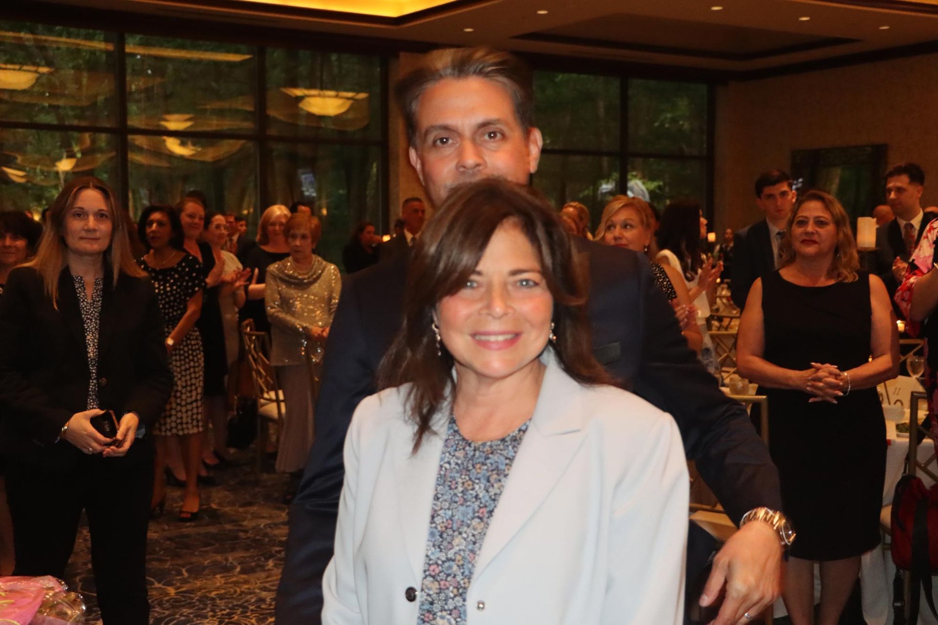 A man and woman are posing for a picture in front of a crowd of people.