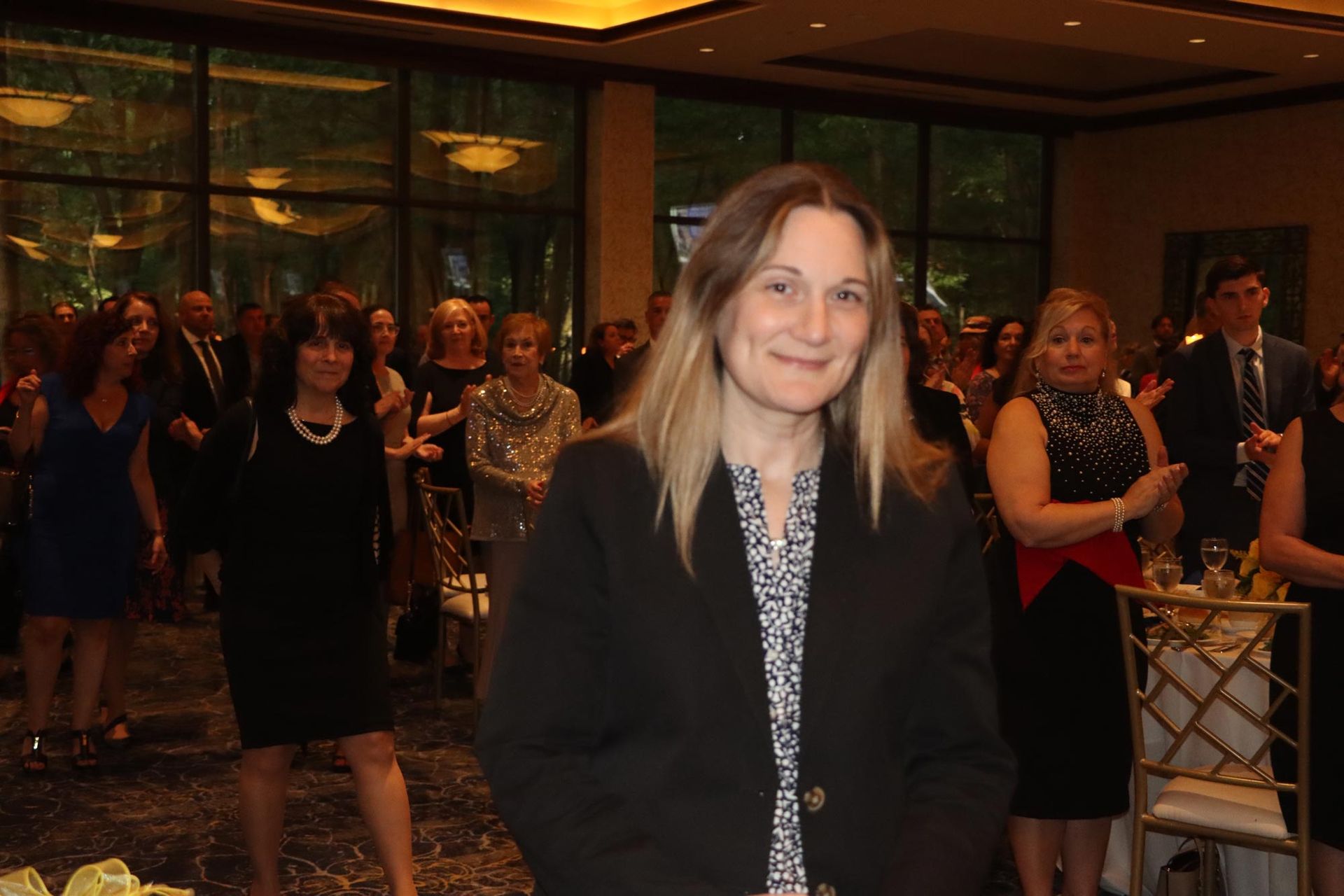 A woman is standing in front of a crowd of people at a party.