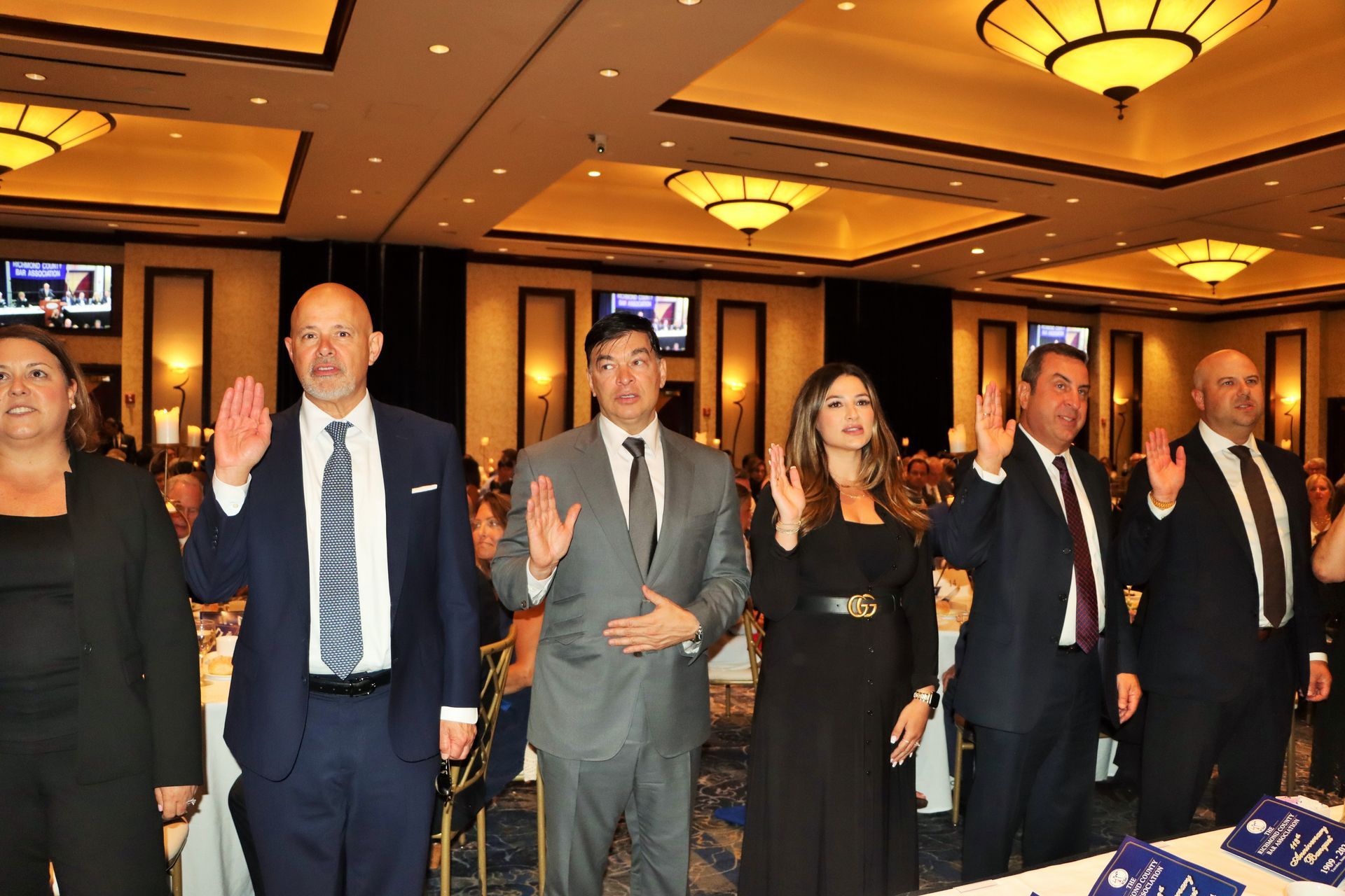A group of people standing in a room with their right hands up