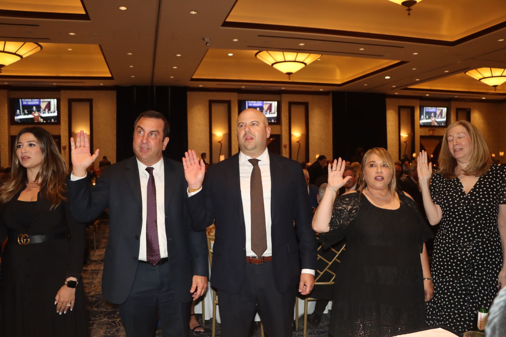 A group of people are standing in a room with their hands in the air.