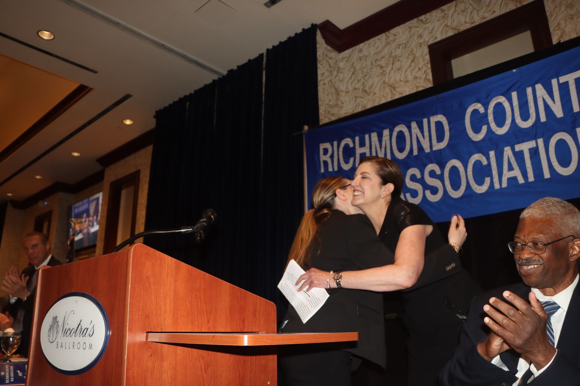 Two women hugging in front of a sign that says richmond county bar association