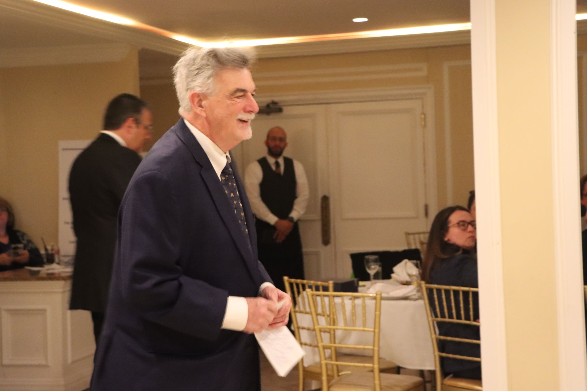 A Man In A Suit And Tie Is Standing In A Room Holding A Piece Of Paper — Staten Island, NY — RCBA