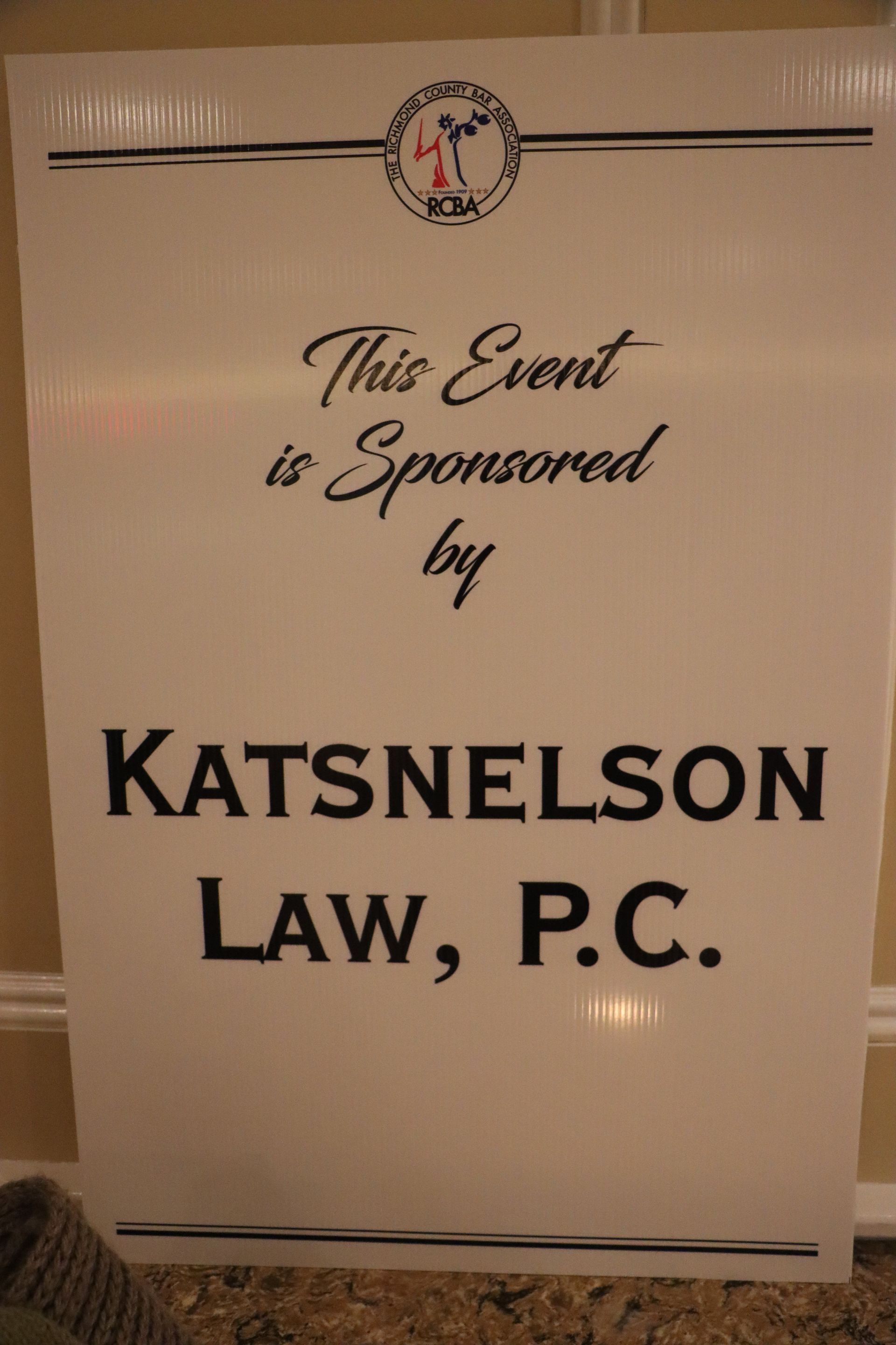 A Sign That Says This Event Is Sponsored By Katsnelson Law P.C — Staten Island, NY — RCBA