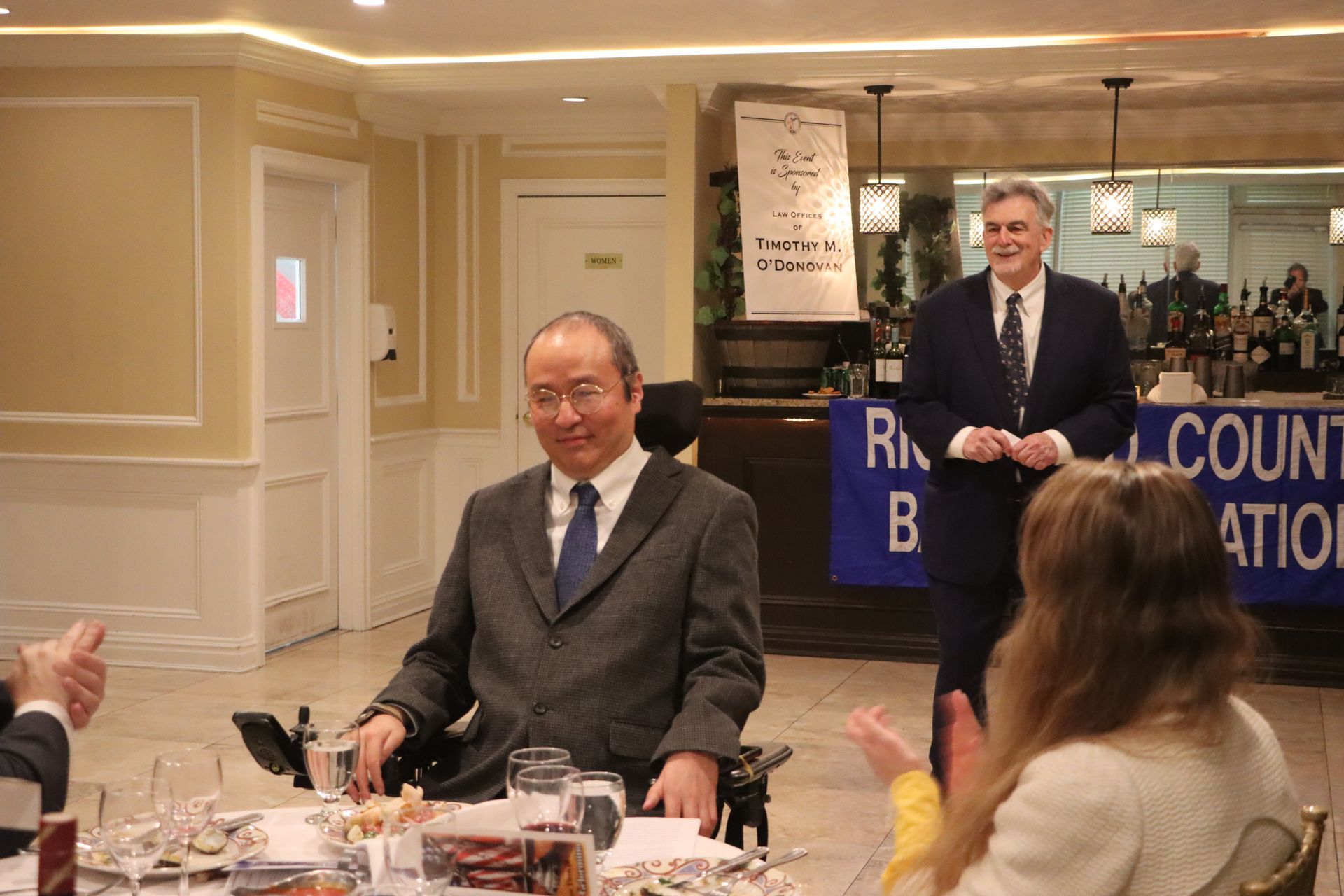 A Man In A Suit And Tie Is Sitting In A Wheelchair At A Table — Staten Island, NY — RCBA