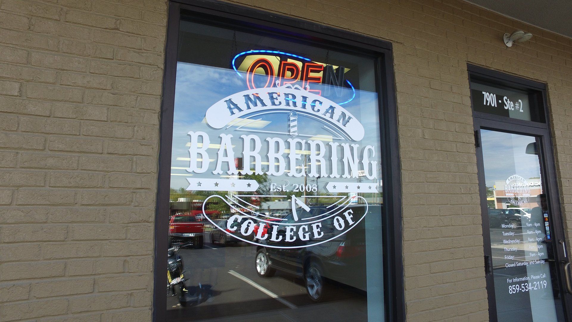 A brick building with a window that says american barbering college of barbering