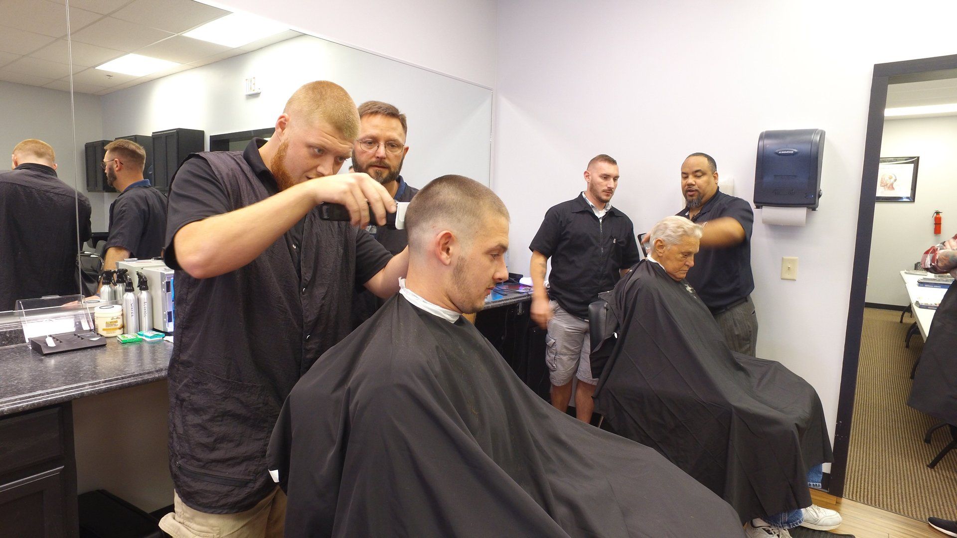 A group of men are getting their hair cut at a barber shop.