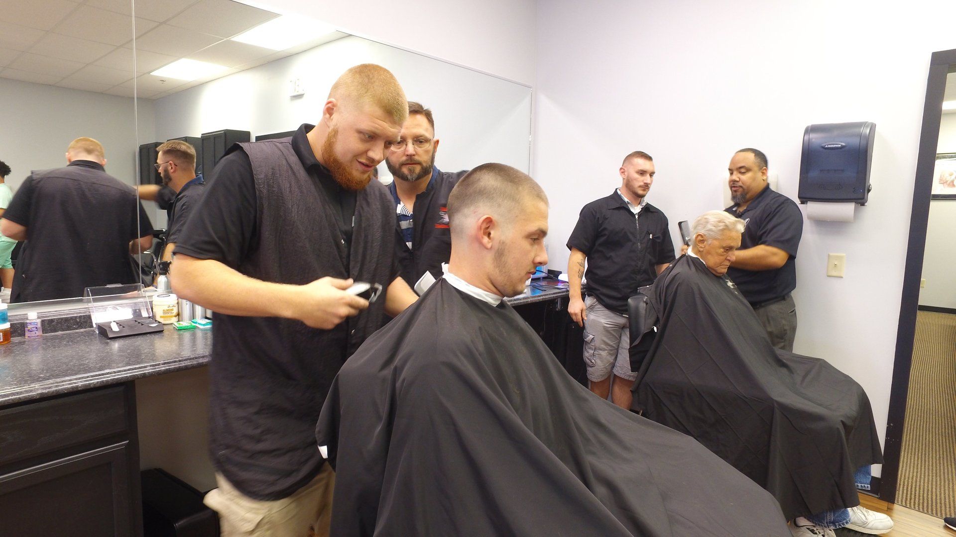 A man is getting his hair cut by a barber in a barber shop.
