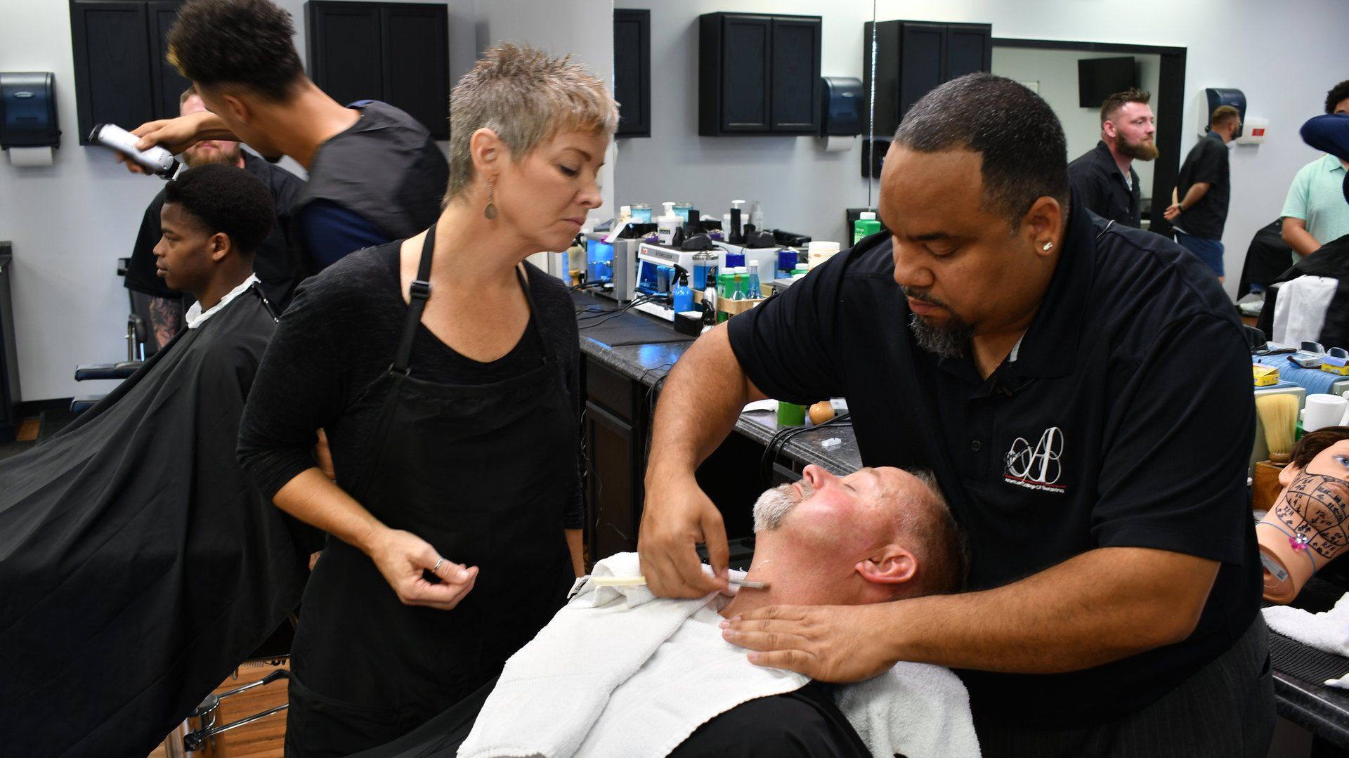 A man is getting his beard shaved by a barber in a barber shop.