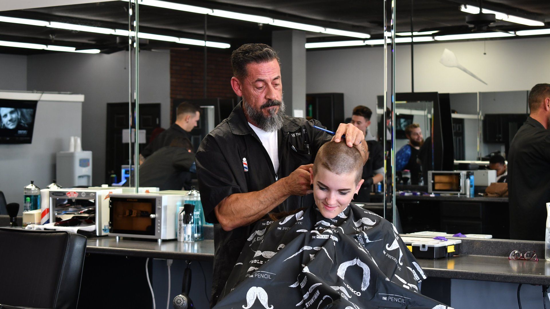 A man is cutting a man 's hair in a barber shop.