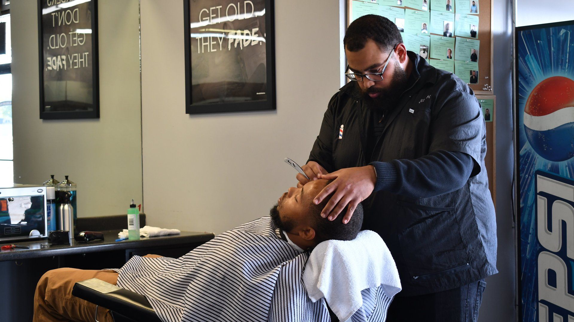 A man is getting his hair cut by a barber in a barber shop.