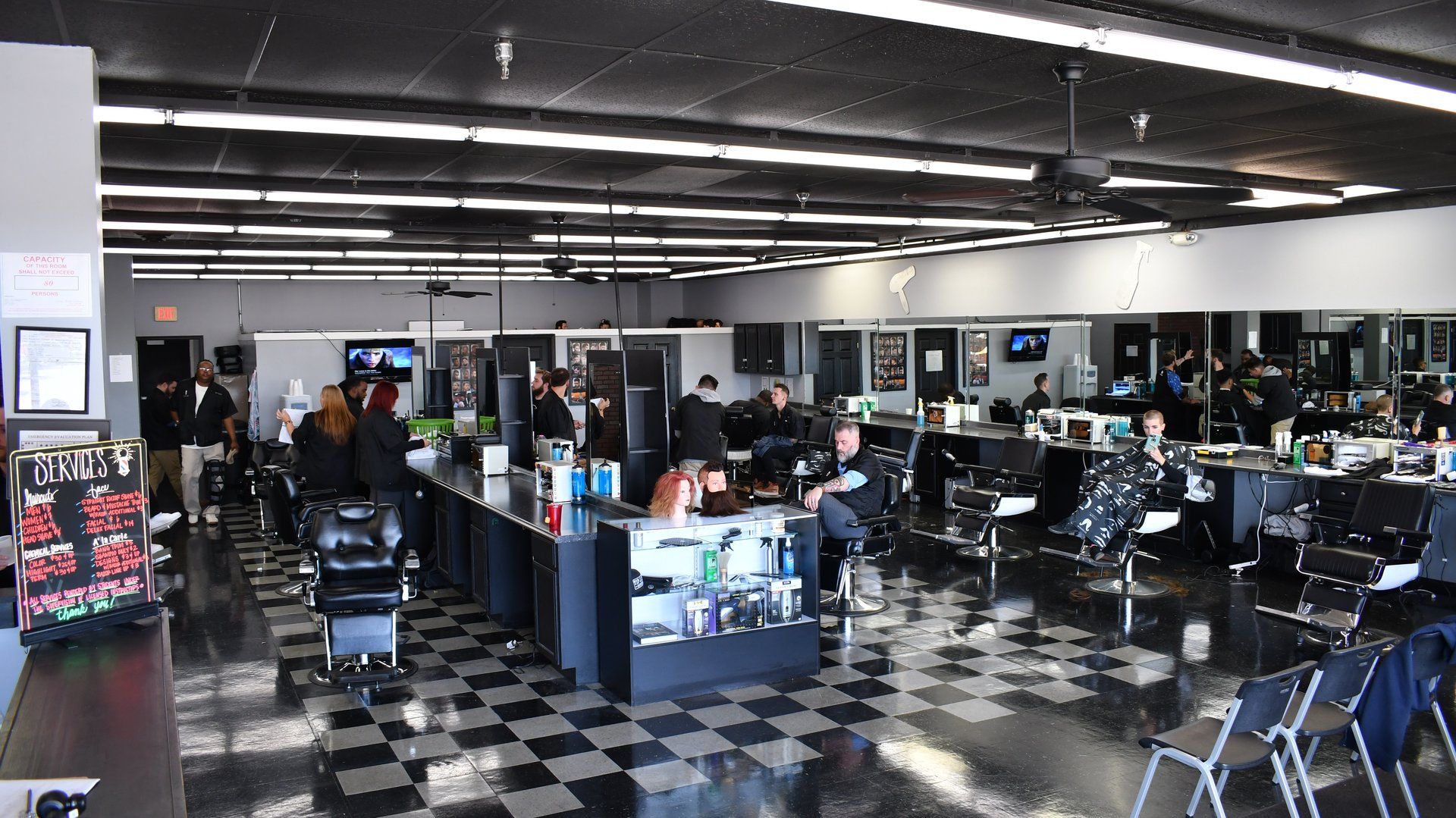 A large barber shop with a checkered floor and lots of chairs.