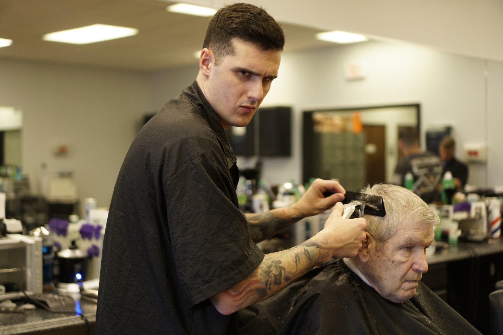 A man is getting his hair cut by a barber in a barber shop.