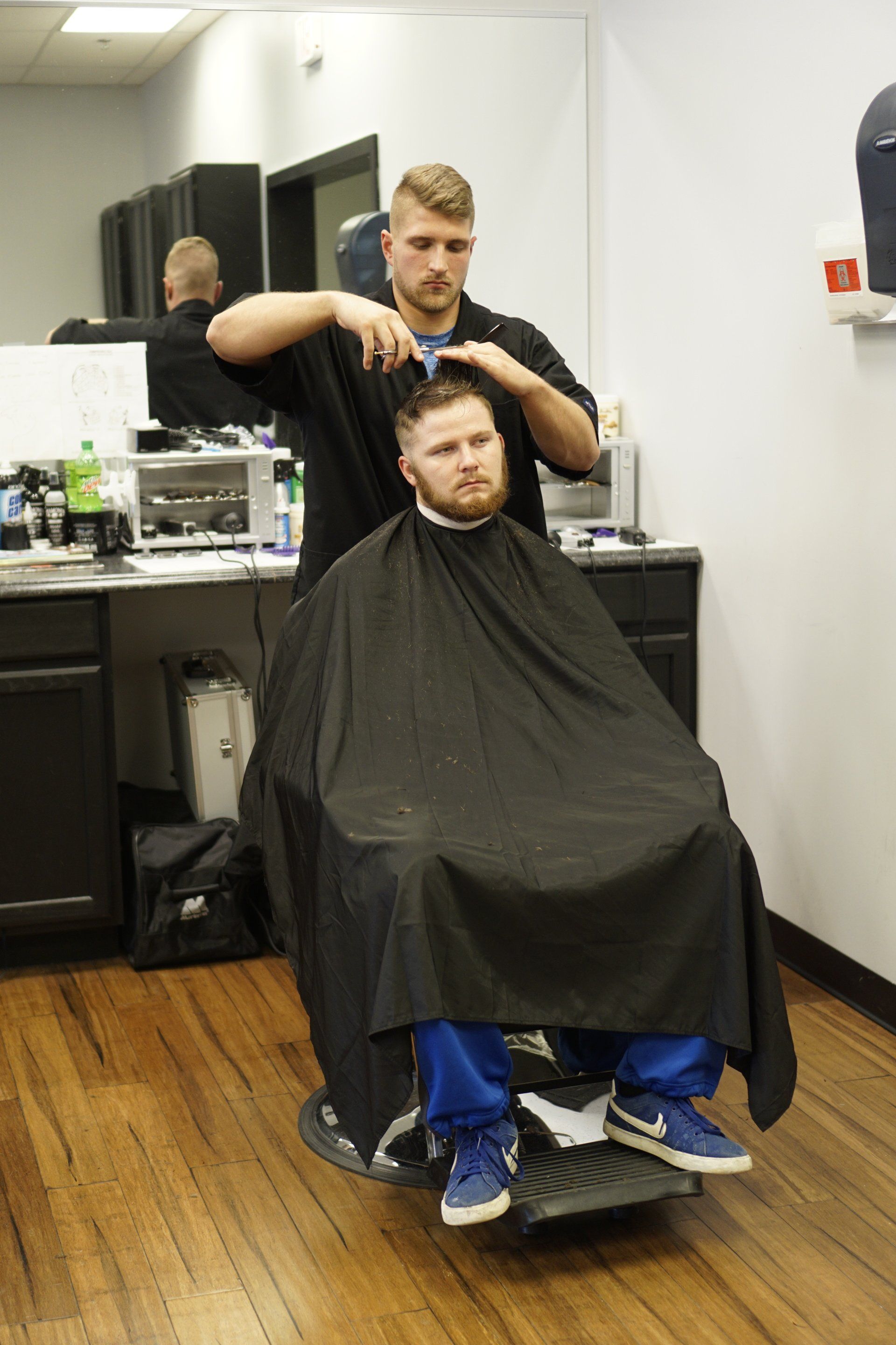 A man is getting his hair cut by a barber in a barber shop.