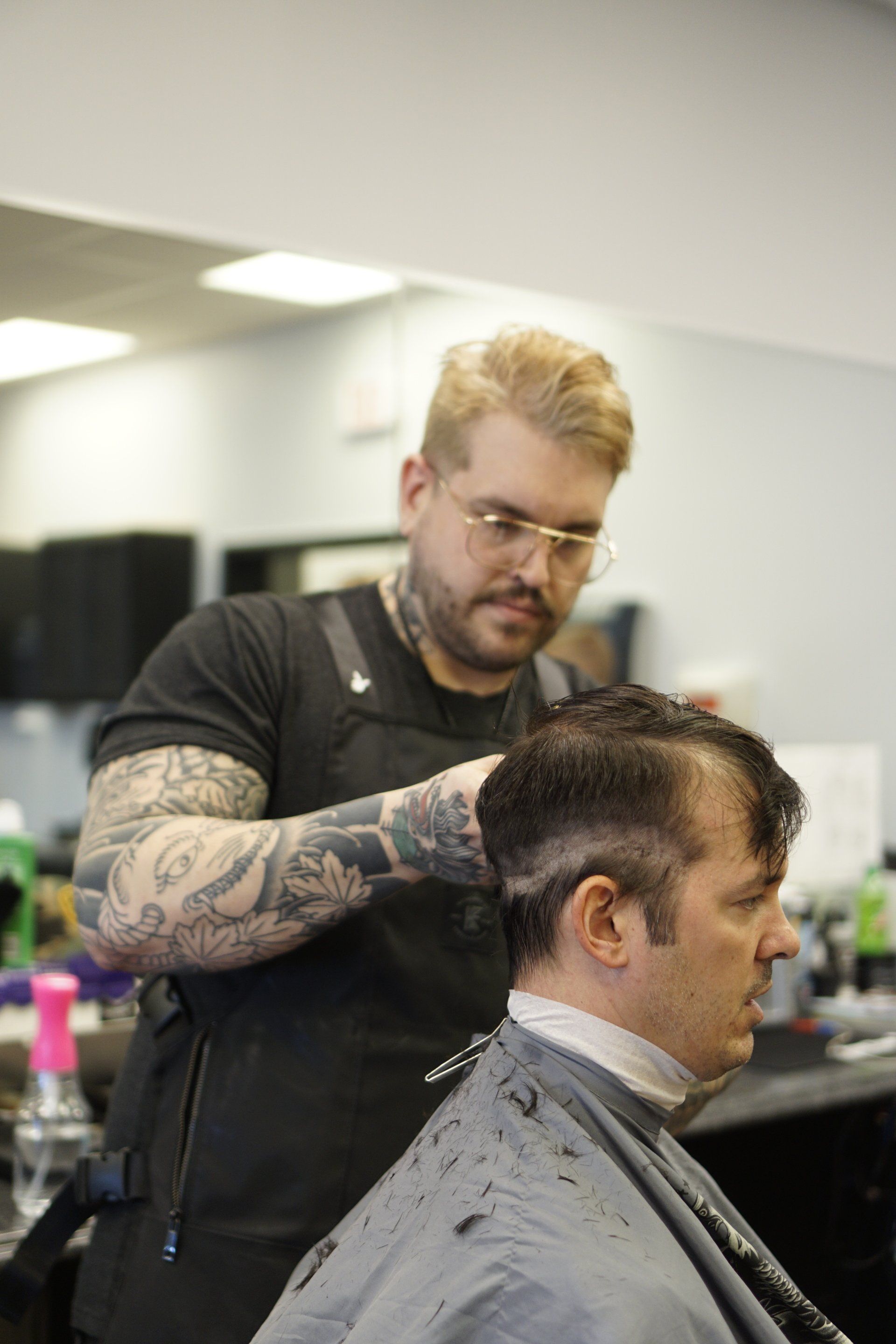A man is getting his hair cut by a barber in a barber shop.