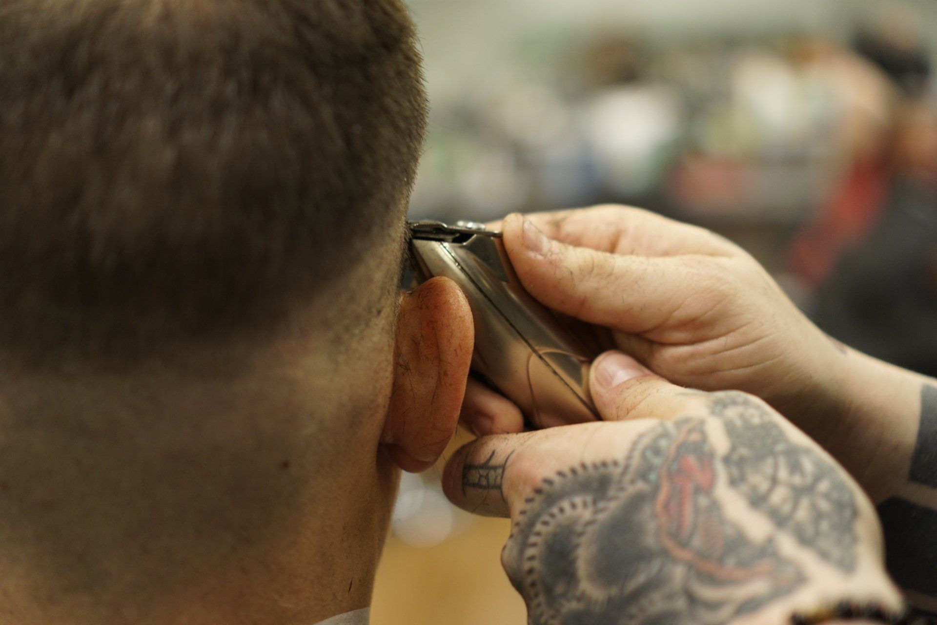 A man is getting his hair cut by a barber with a tattoo on his hand.