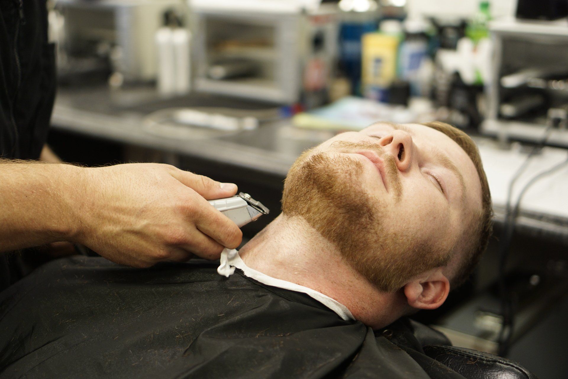 A man is getting his beard cut by a barber in a barber shop.