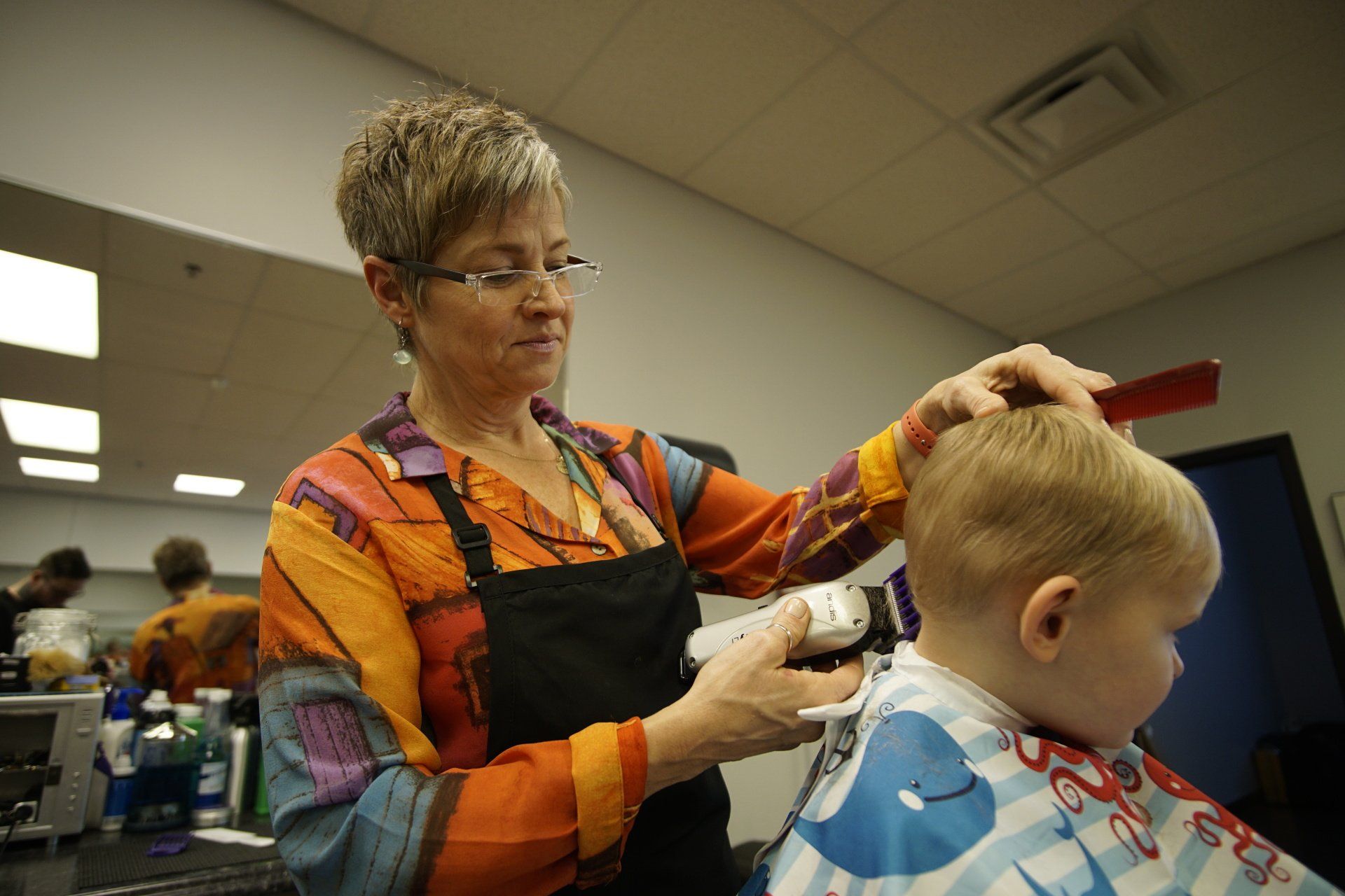 A woman is cutting a baby 's hair in a salon.