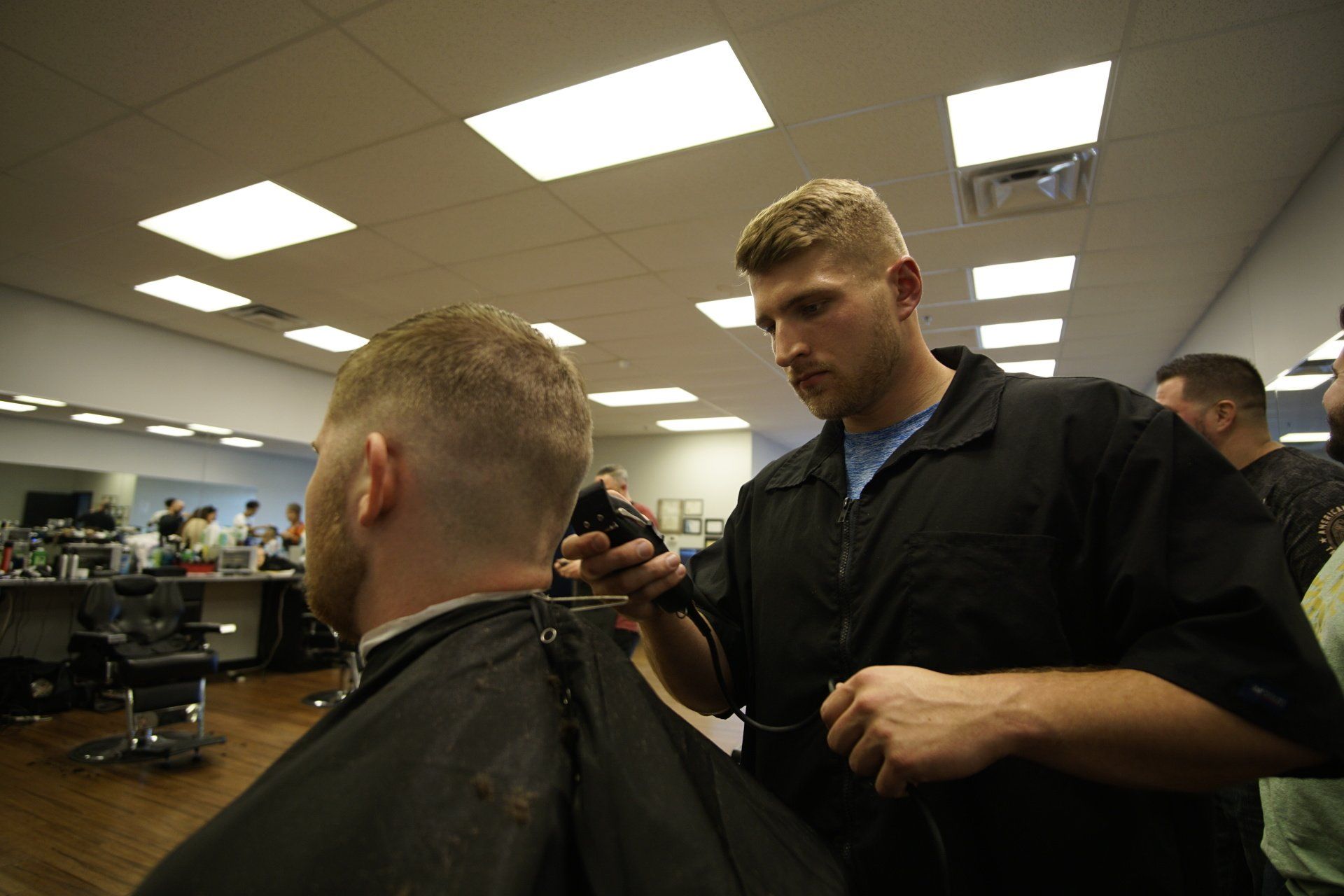 A man is getting his hair cut by a barber in a barber shop.