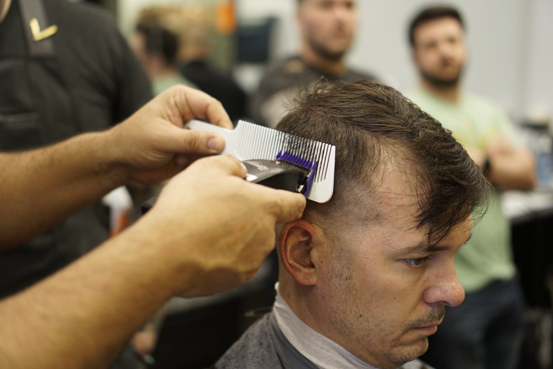 A man is getting his hair cut by a barber in a barber shop.
