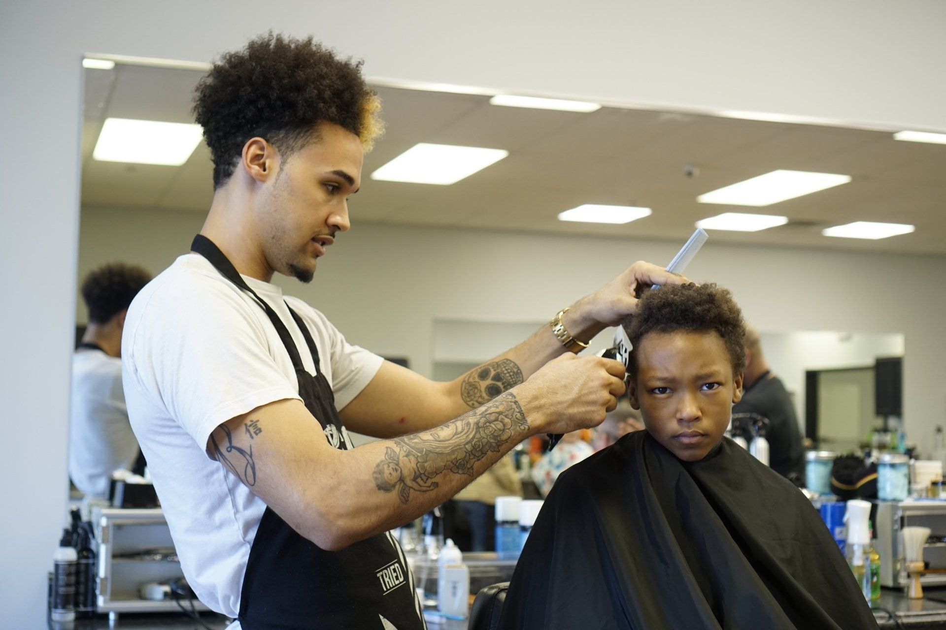 A young boy is getting his hair cut by a barber in a salon.