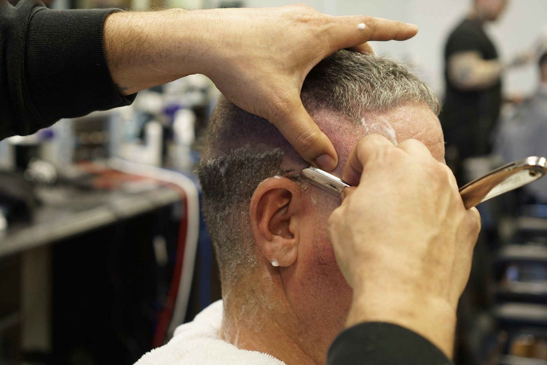 A man is getting his hair cut by a barber with a razor