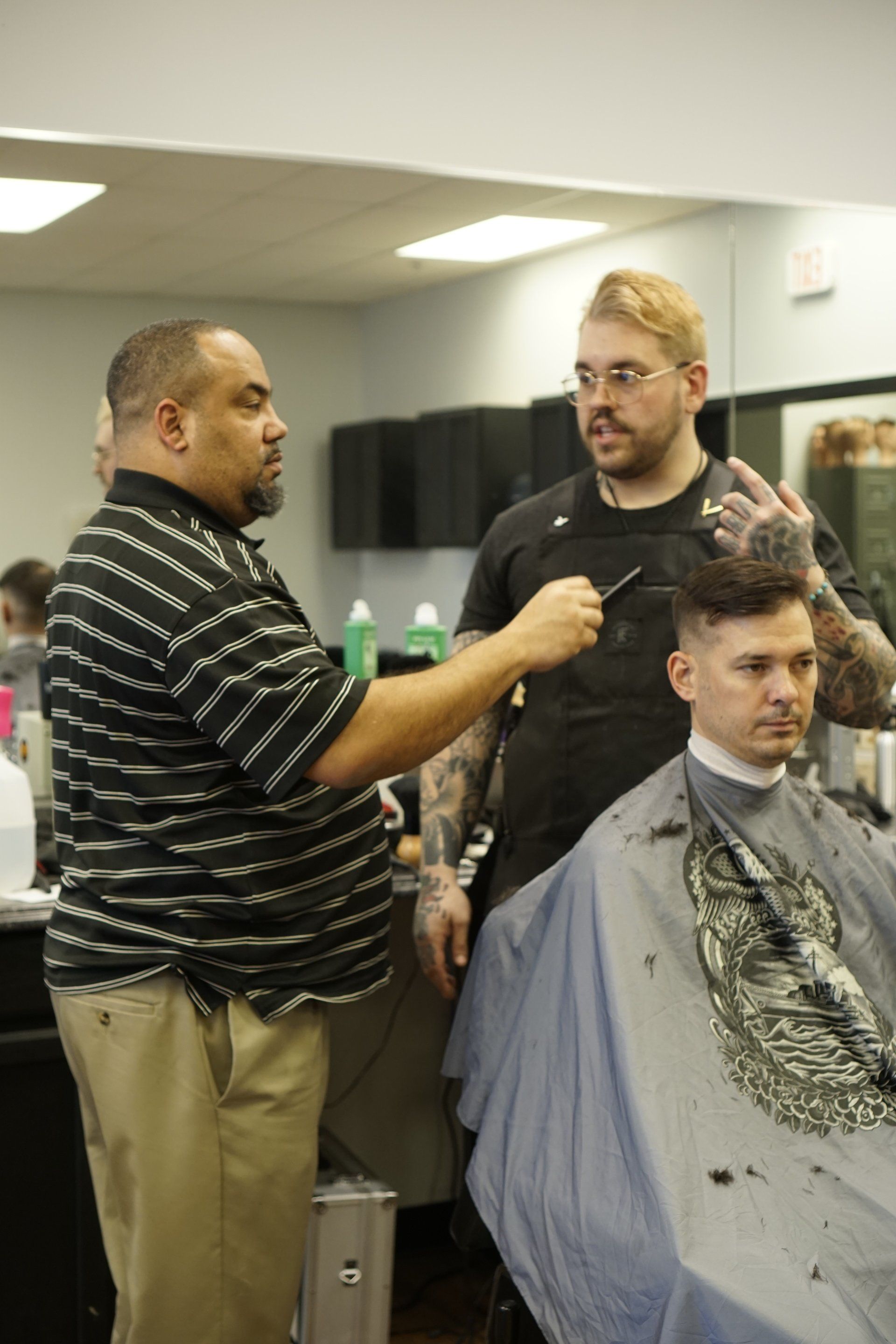 A man is getting his hair cut by a barber in a barber shop.