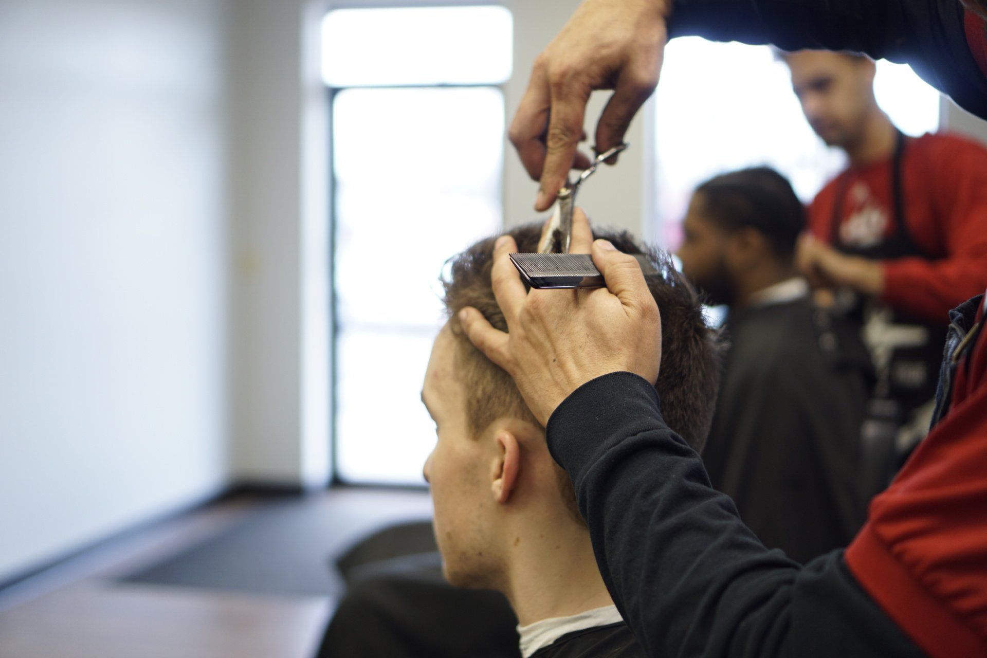 A man is getting his hair cut by a barber in a barber shop.