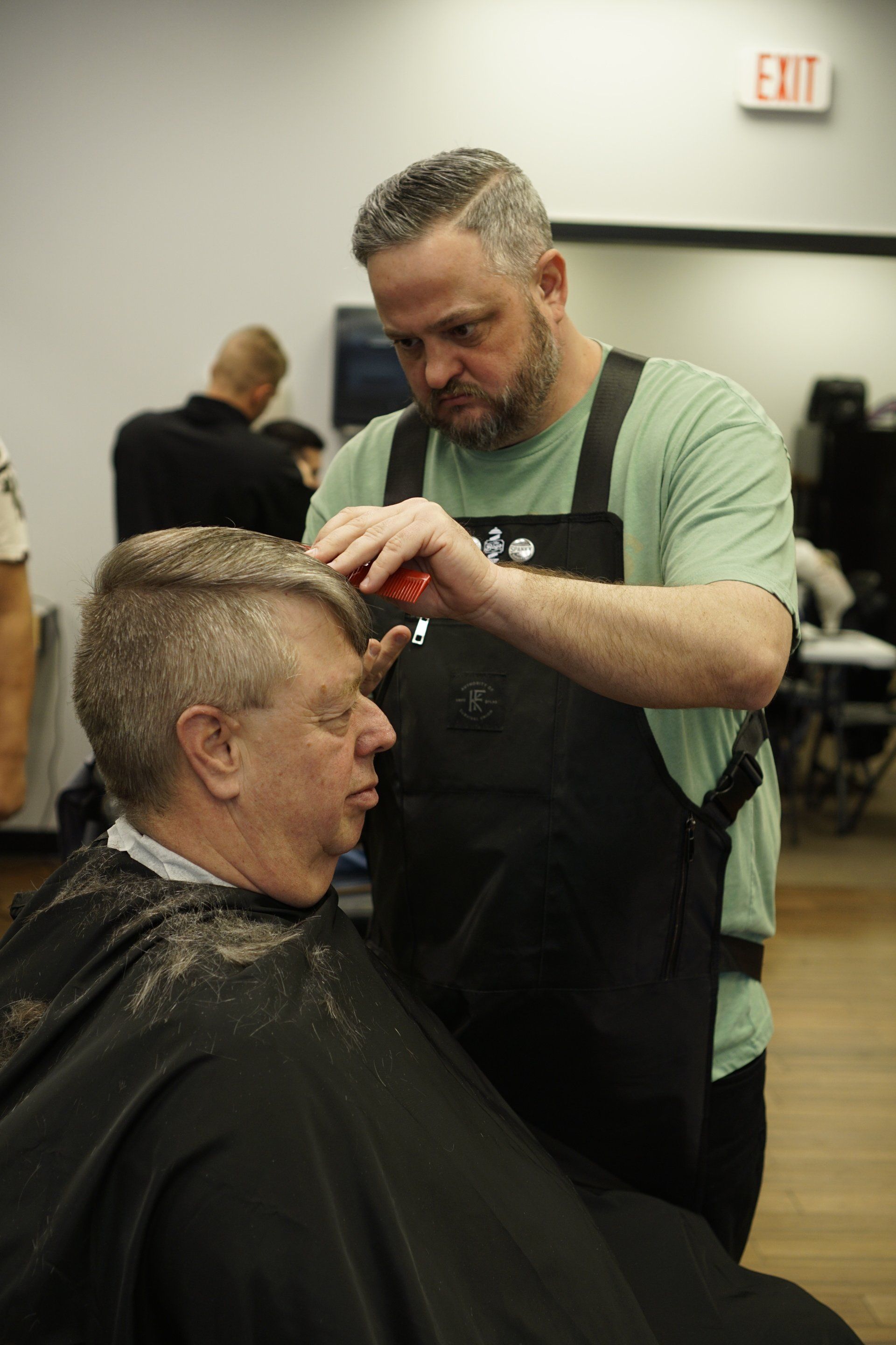 A man is getting his hair cut by a barber in a barber shop.