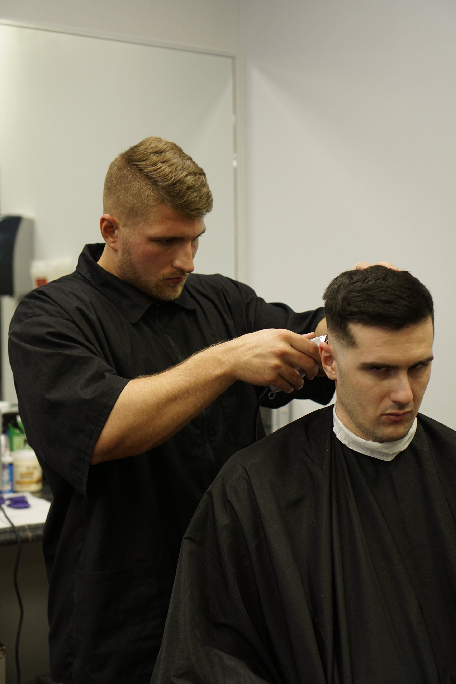 A man is getting his hair cut by a barber in a barber shop.