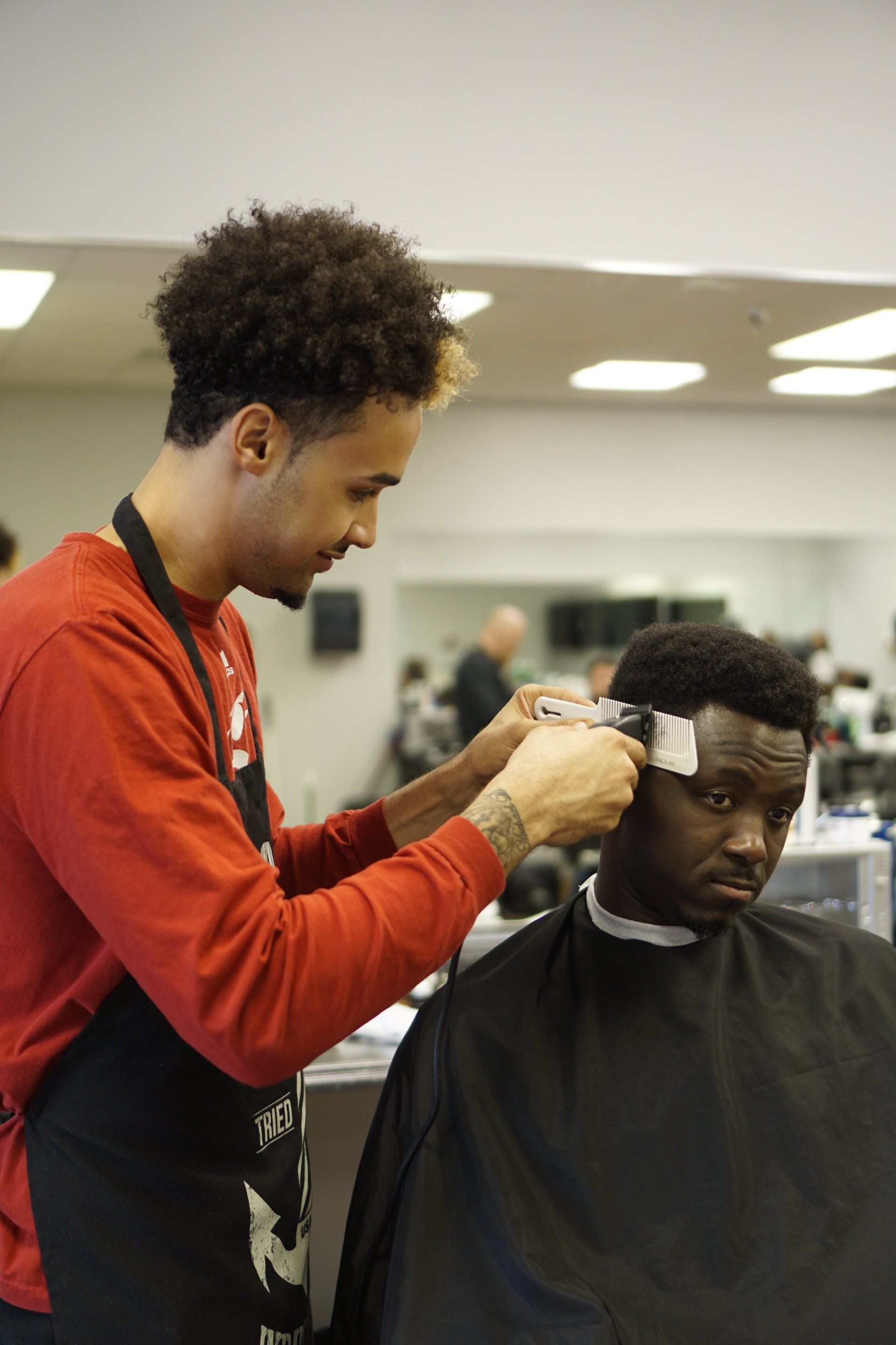 A man is getting his hair cut by a barber in a barber shop.