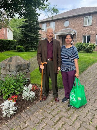 A man with a cane is standing next to a woman holding a green bag.