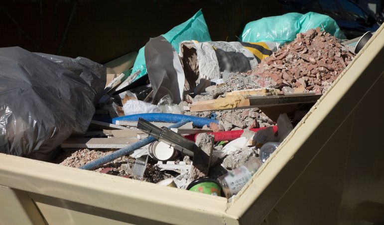 A dumpster filled with a lot of trash and junk. A dumpster filled with a lot of trash and junk.