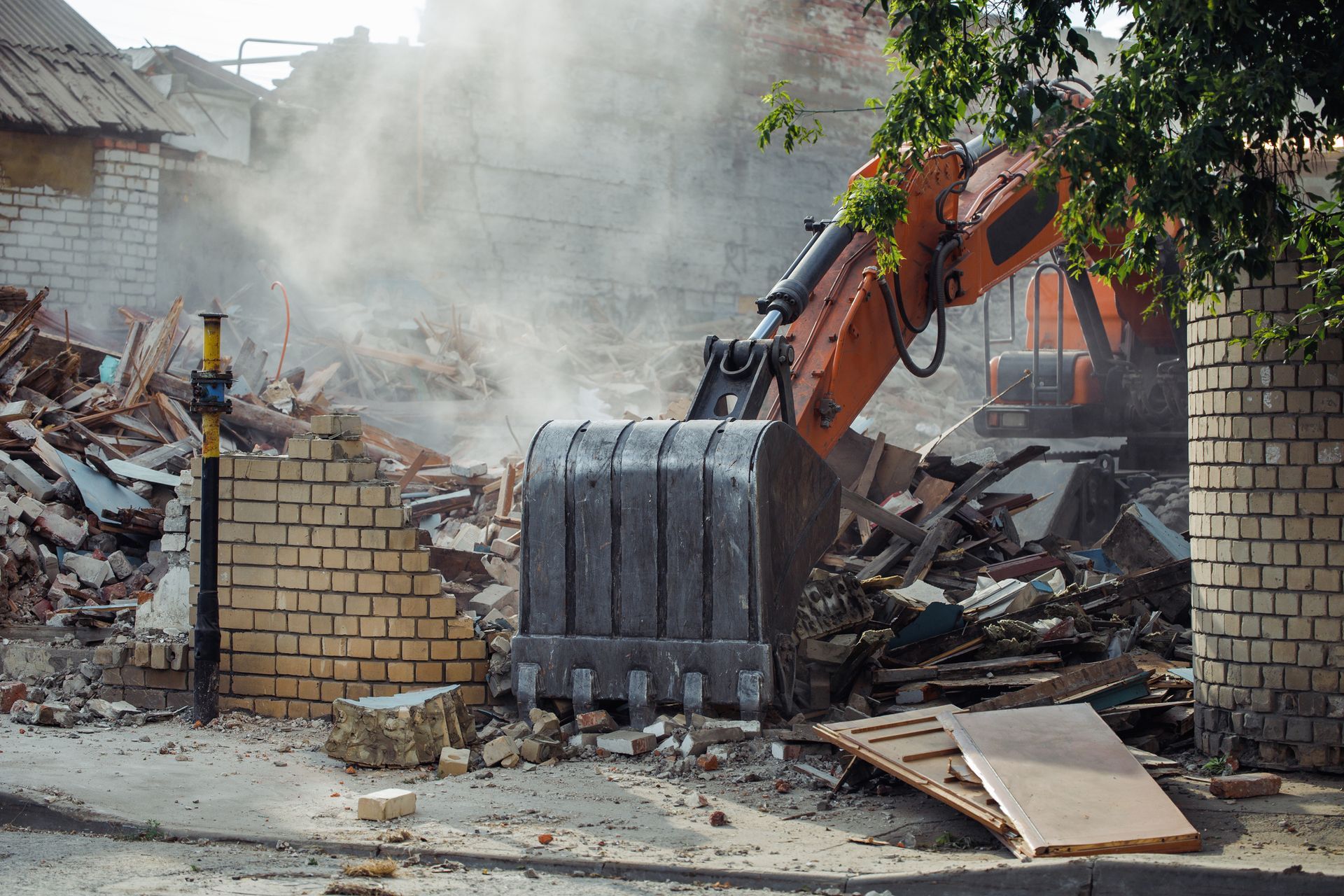 A bulldozer is demolishing a brick building.