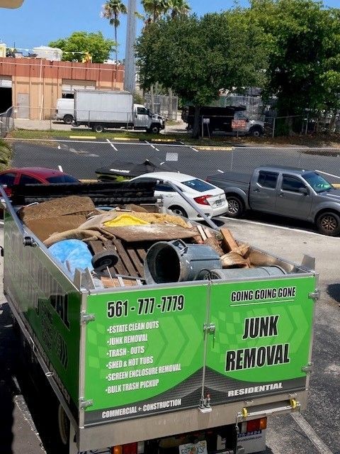 A green junk removal truck is parked in a parking lot.