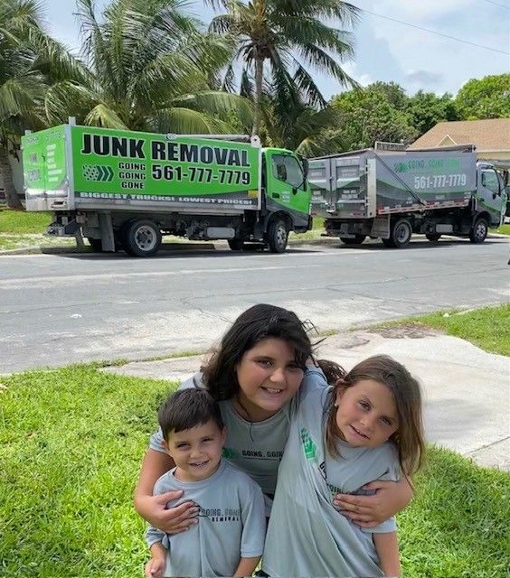 A woman and two children are posing for a picture in front of a junk removal truck.
