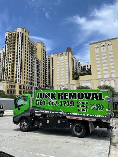 A junk removal truck is parked in front of a building