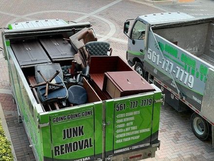 A green garbage truck is parked on a cobblestone street.