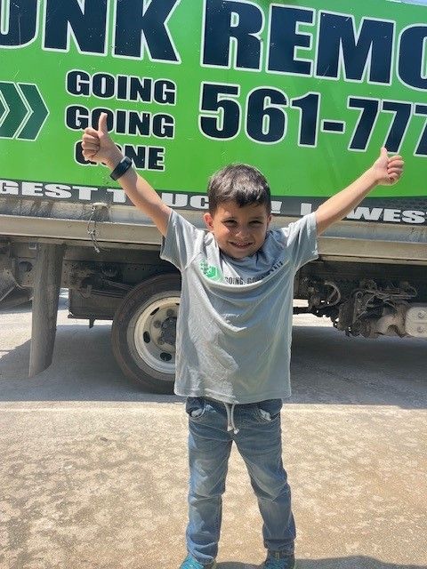 A young boy giving a thumbs up in front of a junk removal truck