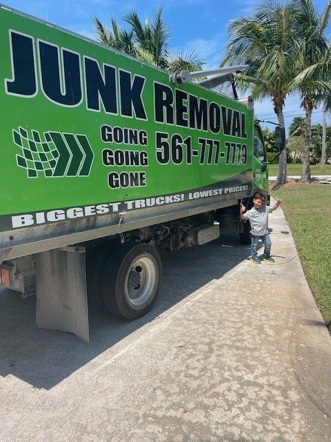 A little boy is standing in front of a junk removal truck
