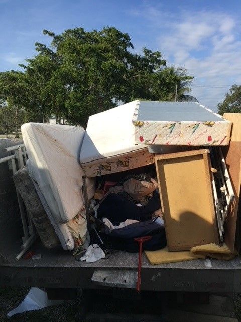 A pile of junk on the back of a truck including a mattress