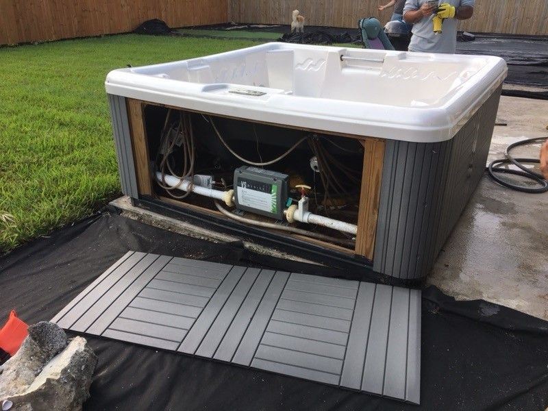 A man is working on a hot tub in a backyard.