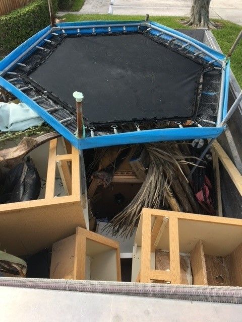 Two men are loading garbage into a garbage truck.