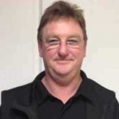 Man in glasses and black shirt smiles at the camera.