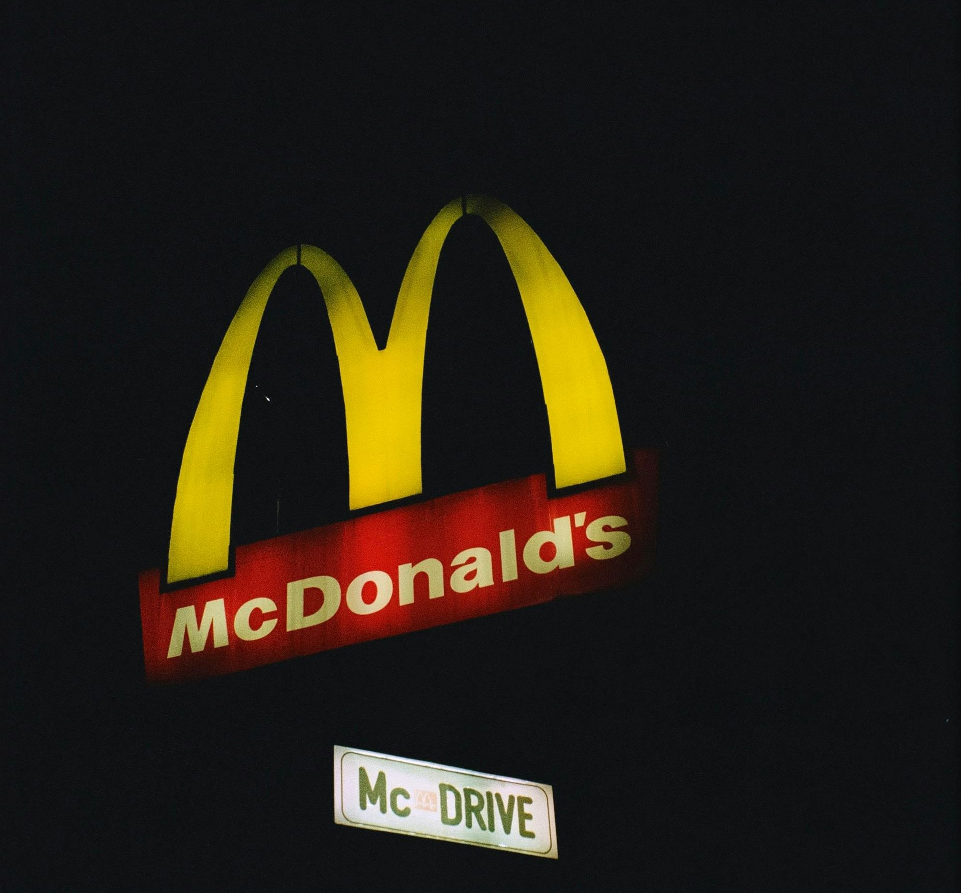 McDonald's illuminated logo with golden arches and red background, with 