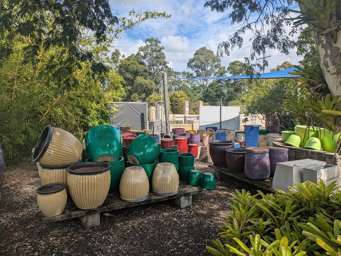 A Bunch of Potted Plants Are Sitting on a Table in a Greenhouse — Golden City Gympie Brick & Landscape in Gympie, QLD