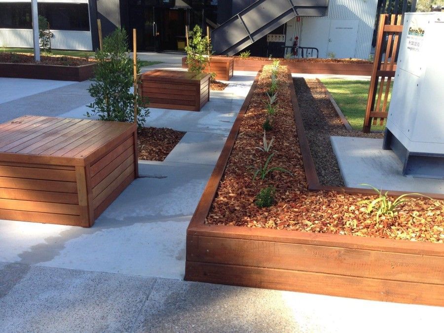 A Concrete Walkway With Wooden Benches and Planters — Golden City Gympie Brick & Landscape in Gympie, QLD